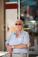 Elderly man waiting at a table outside a store