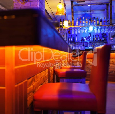 Seats in a brightly lit cocktail bar or nightclub