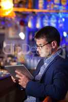 Businessman reading a tablet in a cocktail bar