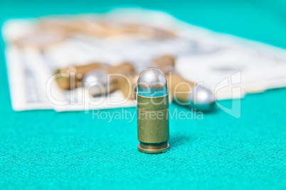 Dollars and casino chips and pistol bullet on a green cloth