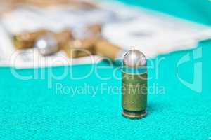 Dollars and casino chips and pistol bullet on a green cloth