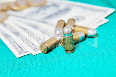 Dollars and casino chips and pistol bullet on a green cloth