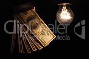 Hanging light bulb dangle on a wire illuminating bank notes