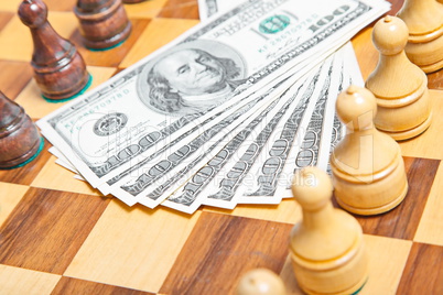 US dollars and chess figures on an old wooden chessboard