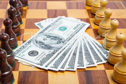 US dollars and chess figures on an old wooden chessboard