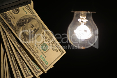 Hanging light bulb dangle on a wire illuminating bank notes