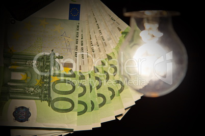 Hanging light bulb dangle on a wire illuminating bank notes