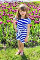 young girl stands by lilac tulips