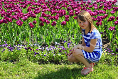 little girl sitd by lilac tulips