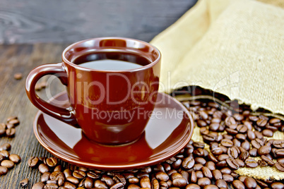 Coffee in brown cup with grains and bag on board