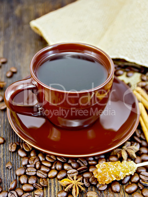 Coffee in brown cup with sugar and bag on dark board
