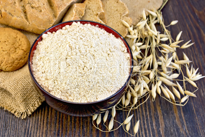 Flour oat in bowl with bread on sackcloth and board