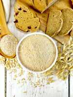 Flour oat in white bowl with bran in spoon on board top