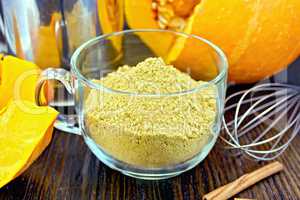 Flour pumpkin in glass cup with sieve and a mixer on board