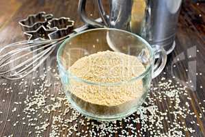 Flour sesame in cup with sieve and mixer on board