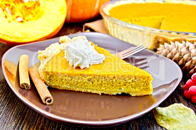 Pie pumpkin in brown plate with cream on board