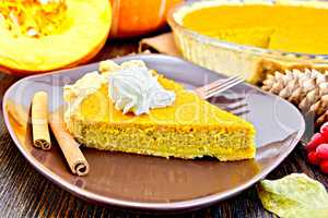 Pie pumpkin in brown plate with cream on board