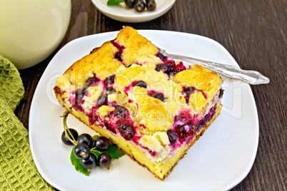 Pie with black currant in plate and fork on board