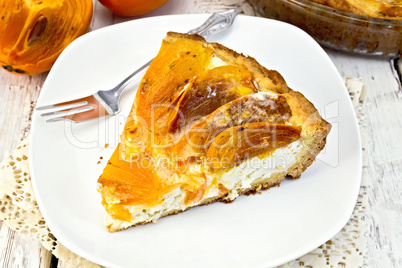 Pie with curd and persimmons with fork in plate on board