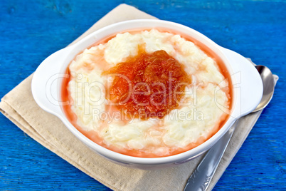 Rice porridge with jam in bowl on blue board