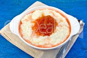 Rice porridge with jam in bowl on blue board