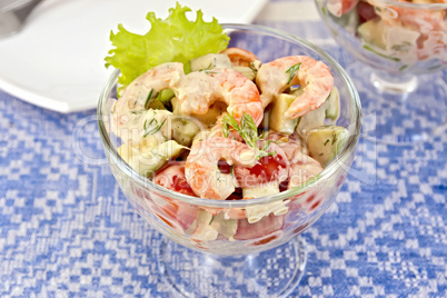 Salad with shrimp and tomatoes in glass on linen tablecloth