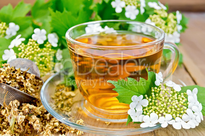 Tea viburnum flowers in glass cup on wooden board