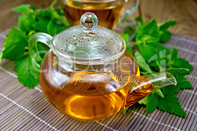 Tea with mint in glass teapot on wooden board