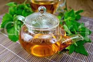 Tea with mint in glass teapot on wooden board