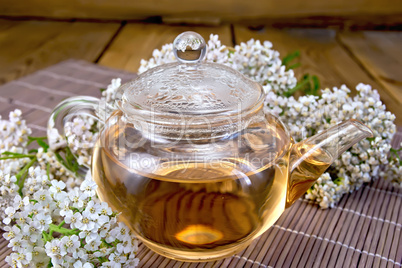 Tea with yarrow in glass teapot on bamboo