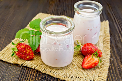 Yogurt with strawberries in jars on sacking