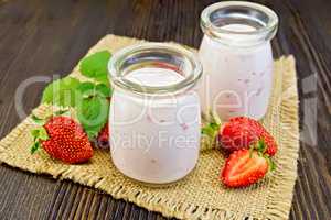 Yogurt with strawberries in jars on sacking