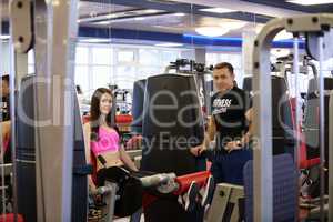 In gym. Fitness trainer and girl posing at camera