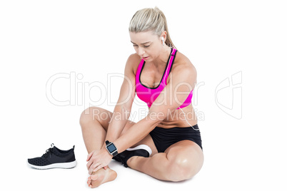 Injured female athlete sitting and touching ankle