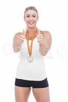 Female athlete wearing a medal and showing thumbs up