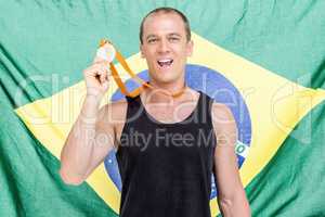 Athlete showing his gold medal in front of brazilian flag