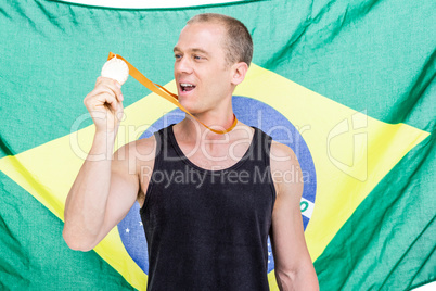 Athlete showing his gold medal in front of brazilian flag