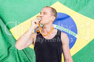 Athlete posing with gold medal in front of brazilian flag