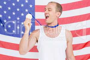 Athlete showing his gold medal in front of american flag