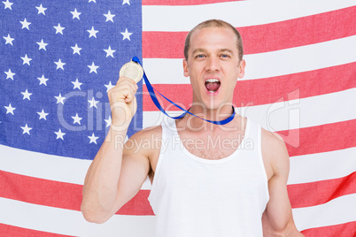 Athlete showing his gold medal in front of american flag