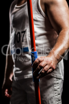 Mid section of athlete standing with javelin