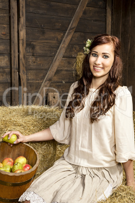 Young country woman with a fruit basket in the barn