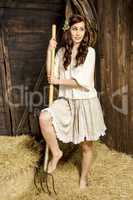 Young woman with fork in the barn