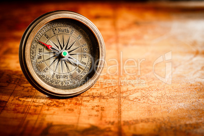 Vintage compass lies on an ancient world map.