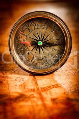 Vintage compass lies on an ancient world map.