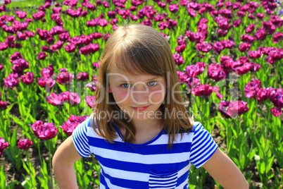 little girl stand by lilac tulips