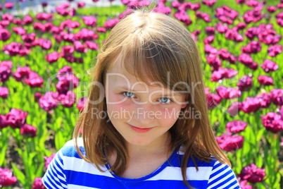 portrait of little girl stand by lilac tulips