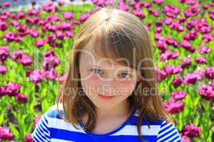 portrait of little girl stand by lilac tulips