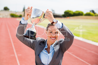 Portrait of happy businesswoman holding up a trophy