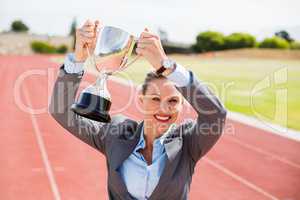 Portrait of happy businesswoman holding up a trophy